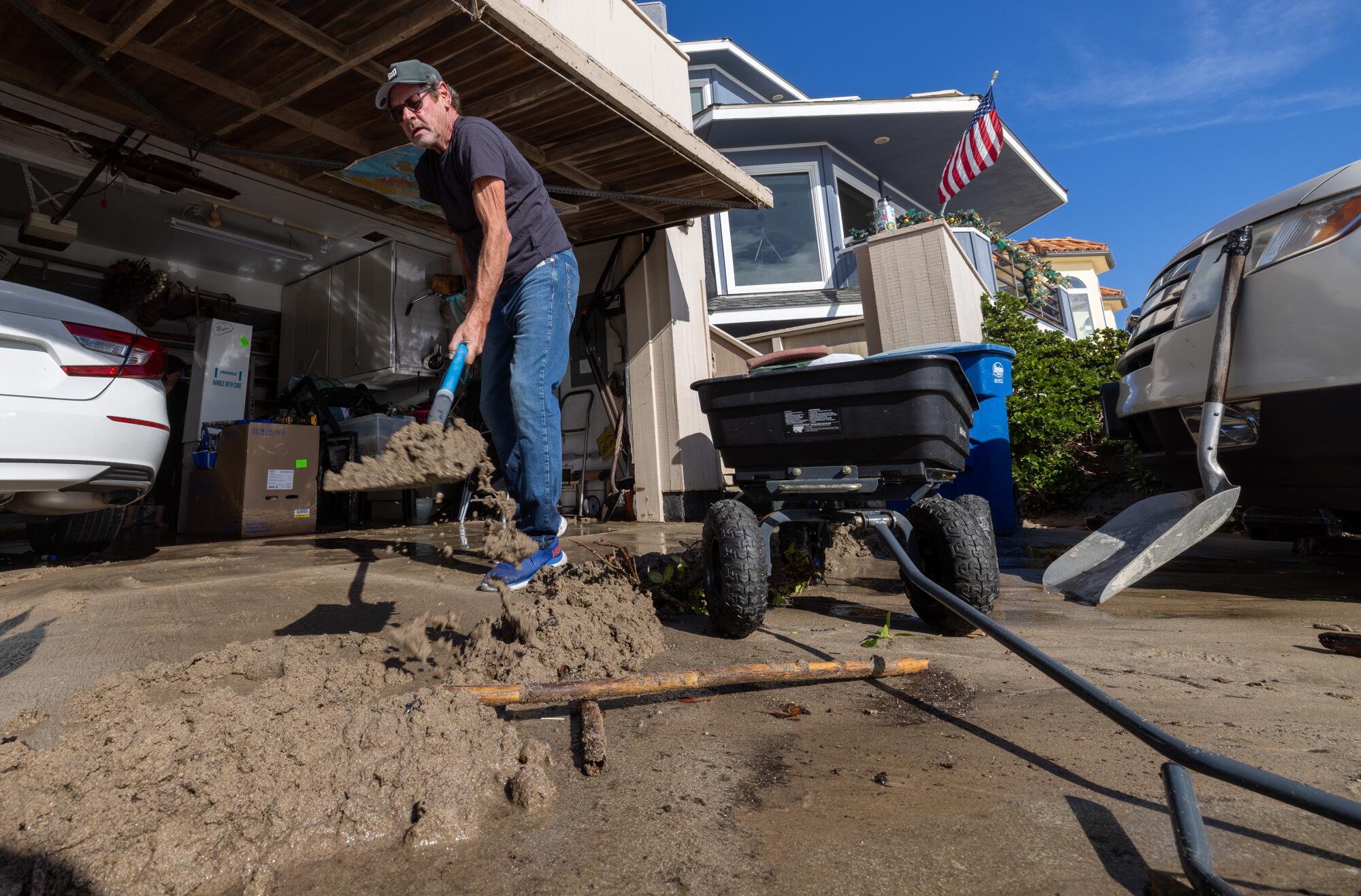 Pierpont resident Ted Teetsel shovels sand out of neighbor Linda Fisher's garage on Greenock Lane after the area was flooded.