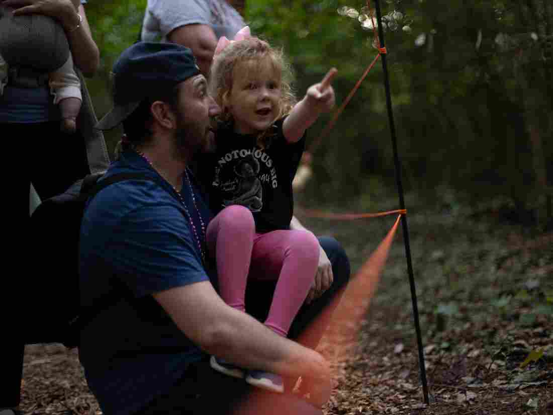 Michael Dunleavy, of Columbia, S.C., holds his daughter Aurora, 4, as they watch fireflies at Congaree National Park on May 16, 2024, in Hopkins, S.C. Visitors had to enter a lottery to get tickets to see the fireflies during their mating season.