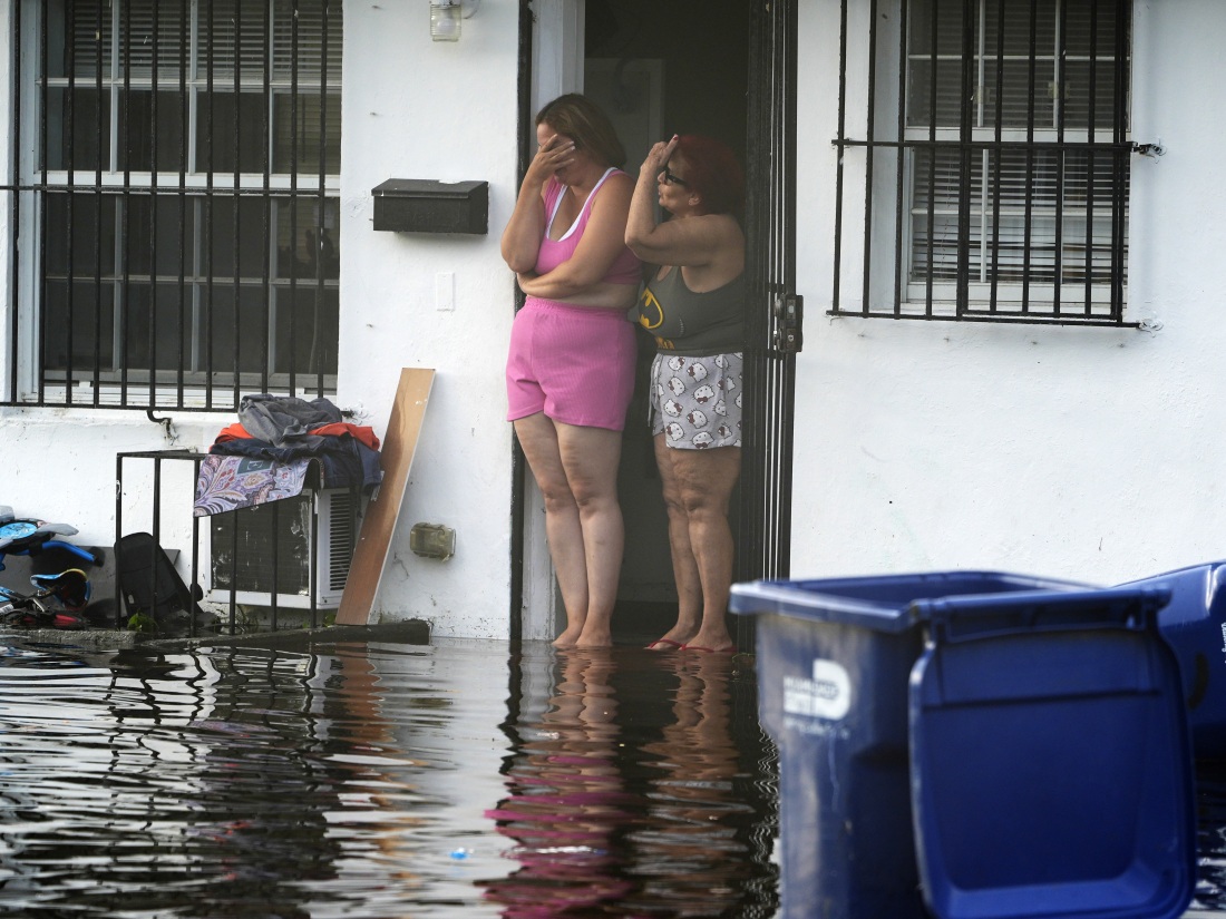 Two women react as they see flooding on their street on Thursday, June 13, 2024, in North Miami, Fla.